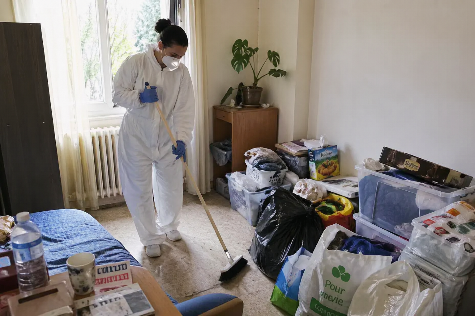 Personne en combinaison de protection nettoyant un logement encombré après un syndrome de Diogène pour éviter le retour de l’insalubrité