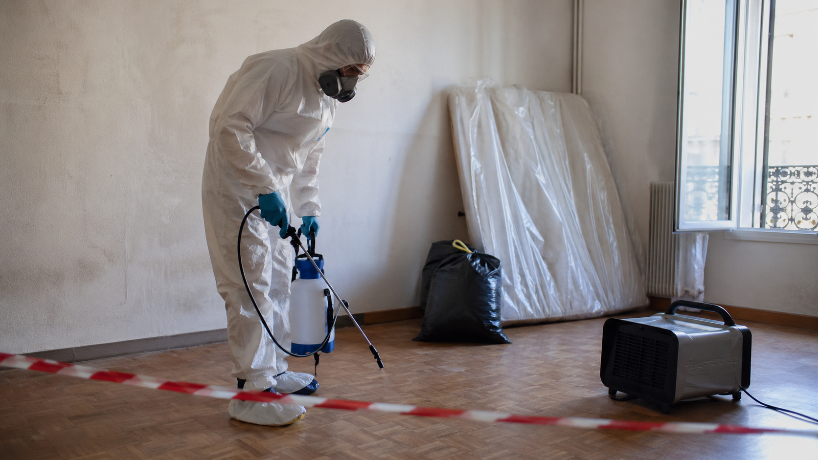 Technicien en combinaison de protection réalisant un traitement professionnel des odeurs incrustées après décès dans un logement