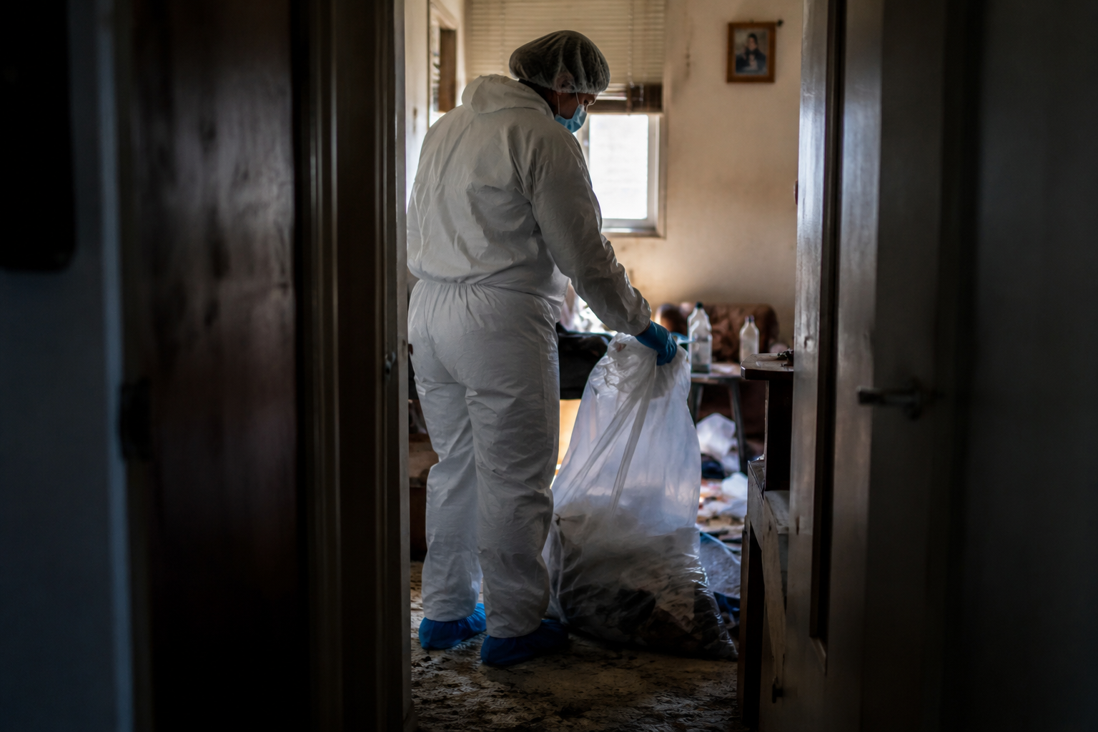 Nettoyage discret après syndrome de Korsakoff Professionnel en tenue de protection réalisant un nettoyage discret dans un logement encombré après syndrome de Korsakoff